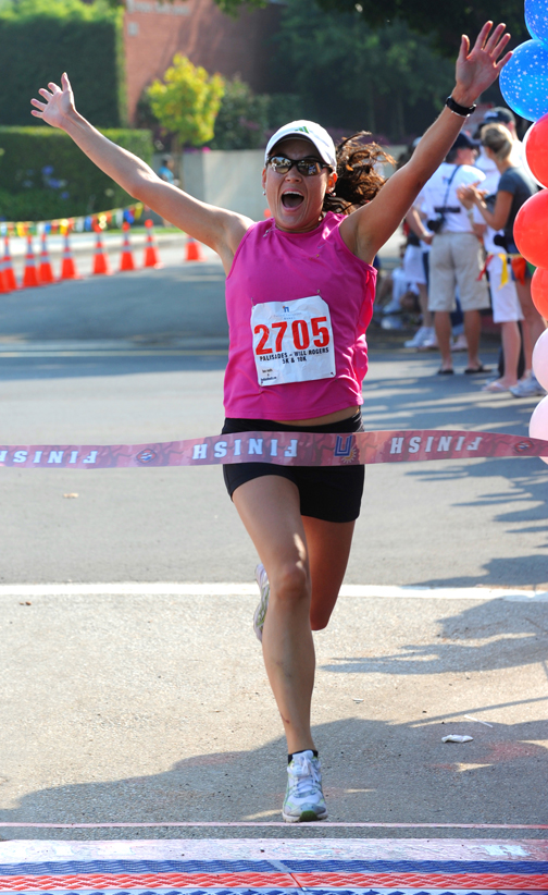 Vivien Wadeck raises her arms in elation as she hits the tape in the Palisades-Will Rogers race on July 4. The 29-year-old junior from Cal State Los Angeles won the women's 5K in 17:15.