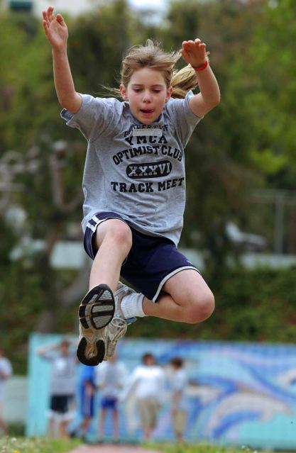 St. Matthew's fourth grader Taylor Pecsok flies through the air in  the long jump event at last Sunday's Optimist/YMCA Youth Track Meet.