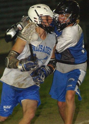 Palisades High attacker Max Gross (left) shields the ball from a defender on his way to a goal against Windward in last Friday night's varsity lacrosse game at Stadium by the Sea. The Dolphins won, 16-6, and remained undefeated.