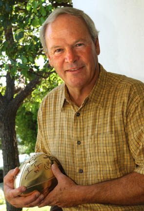 John Huarte stands on the porch of his Huntington Palisades home holding a gold football signed by fellow Heisman Trophy winners. He won the award in 1964 as the quarterback at Notre Dame.