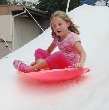 A Coast Sports camper sleds down a hill during snow day.