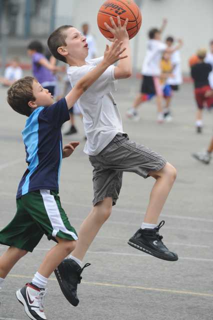 Freddy Cushnir (right) of the Suns drives for a layup against Anthony Spencer of the Bulls during Ben Howland's youth basketball camp last week at Palisades High.
