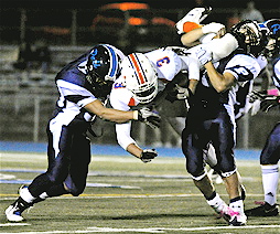 Linebacker Victor Garcia (left) and cornerback Laurence Villasenor (right) tackle University's Bryan Rivas in midair during last Friday night's Western League game at Stadium by the Sea.