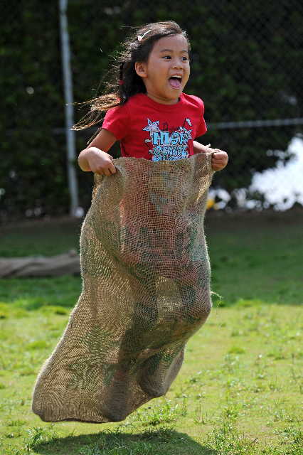 Kindergartener Tess Smigla jumps toward the finish line during the sack race portion of the obstacle course.