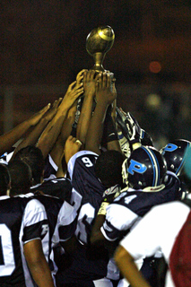 Palisades players raise the Charter Bowl trophy skyward after their resounding 21-0 victory over Granada Hills at Stadium by the Sea.