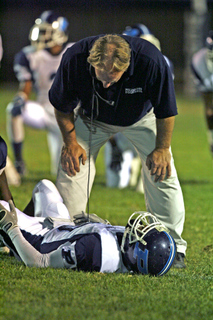 Coach Kelly Loftus stands over running back Tyquion Ballard, who was injured on Palisades' first offensive play and did not return in last Thursday's 42-15 loss at Venice.