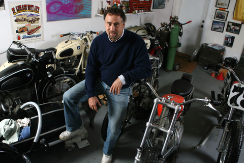Motorcycle enthusiast and new author John Stein, surrounded by several vintage bikes in the garage of his home on Chatauqua.