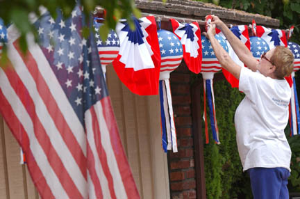 Jackie Leebody hangs Fourth of July decorations on the front porch of her home on Sunset, along the parade route, which has become a tradition for her.