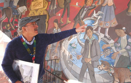 Palisadian Frank Damon, a Las Angelitas del Pueblo docent, points out details in the mural painted between 1974 and 1978 by artist Leo Politi on the Biscailuz Building off Olvera Street.  The 