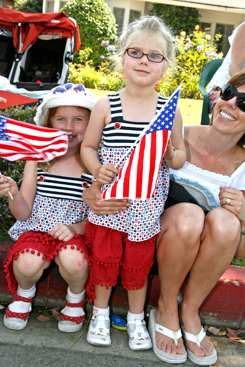 Jenny-Lynn Marais (far right) cheers on the parade with daughters Chloe, 7, and Nieka, 4 (standing), along a stretch of Sunset near Drummond.