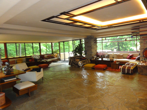 Standing in the Fallingwater living room, the visitor's eye is drawn outward to the southwest terrace just above the falls. The ceiling recess opens to a common space, illuminating the waxed flagstone floors. Wright furnished the interior with built-in and freestanding furniture he designed specifically for the house.  Photo: Libby Motika