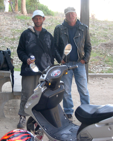 Two of the homeless men who live at the bottom of Temescal Canyon, Rick (left) and Randall Bartoshevich, stand next to Bartoshevish's scooter, which he bought by saving some of the $900 a month he receives from disabiity. The men were watching a recent cleanup of homeless encampments near their hidden belongings. Photo: Sue Pascoe