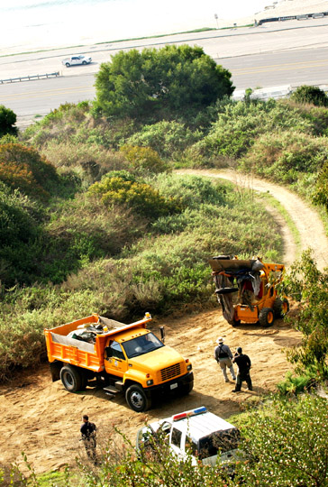 LAPD and Recreation and Parks officials supervise a cleanup effort of homeless encampments on the hillside above PCH, below Via de las Olas. With the aid of two skip loaders, they filled 15 dump trucks with trash.