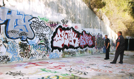 LAPD senior lead officer Chris Ragsdale (left) and Bel-Air Patrol Highlands senior lead officer Aaron Sias inspect the elaborate graffiti in the concrete storm run-off basin adjacent to  Santa Ynez Park in the Highlands.