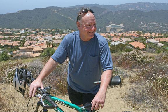 Steve Nuccio with bike above the Palisades Highlands, where he and his wife have lived since 1995.