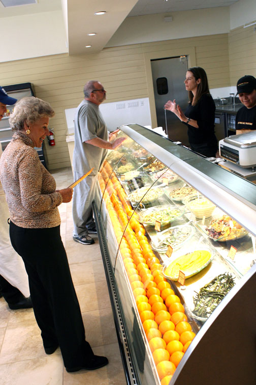 The Village Pantry Director of Operations Sharon Nazitto, behind the deli counter, oversees the first morning's opening as Intima employee Eva Fendel contemplates her breakfast choice.