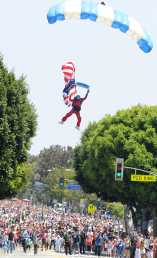 Skydiver Carey Peck, with the American flag trailing behind, was one of four skydivers who landed at the intersection of Sunset Boulevard and Swarthmore Avenue to start Sunday's Palisades Americanism Parade, themed 