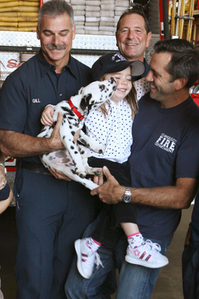 Left to right: Scott Gill, Larry Bauerlein and Ram Miller watch as Smokey, the new Fire Station 69 Dalmatian, tries to lick 4-year-old Gigi Miller, who was born at the station.