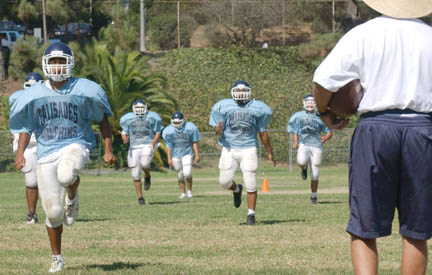 Palisades High offensive coordinator Aaronn Castro (right) is putting his players through rigorous conditioning drills to prepare for the season opener September 9 against Sylmar.