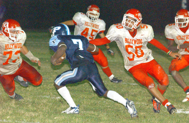 Palisades High quarterback Raymond Elie looks for a place to run as four Hollywood defenders close in during the Dolphins