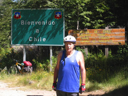 The author takes a rest from mountain biking in front of a sign welcoming visitors from Argentina into Chile.	Photo courtesy of Ezzi Piaggi