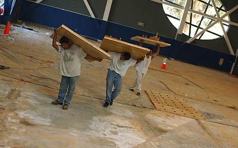 Workers carry wood panels out of the new gym at Palisades Recreation Center last week, the first stage of a three-month project to replace the damaged floor.