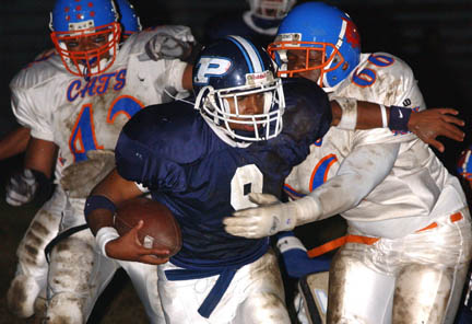 Marquise Coleman tries to break free from the grasp of University defender Ryan Ford in the first quarter of Friday's varsity football game.