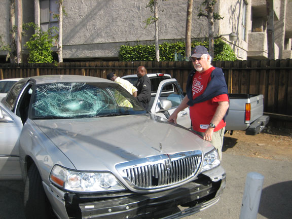 Last Saturday morning in the alley behind Jin's Shell station on the corner of Sunset and Via de la Paz, Rich Wilken (foreground) deliberately parked his car in front of a Lincoln that had been involved in an earlier hit-and-run accident on San Vicente Boulevard. Wilken's action helped prevent the driver from escaping. The driver is being arrested here by an LAPD officer. Photo: Bud Kling